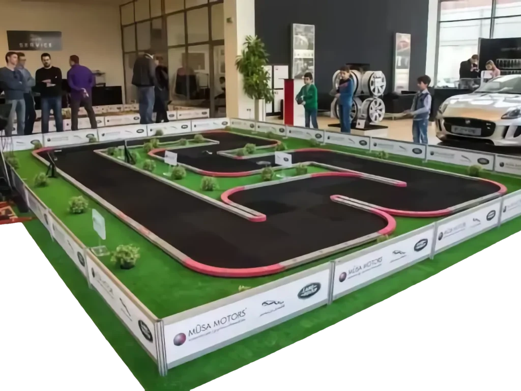 Pista de radiocontrol con barreras y césped decorativo en una exposición de automóviles
