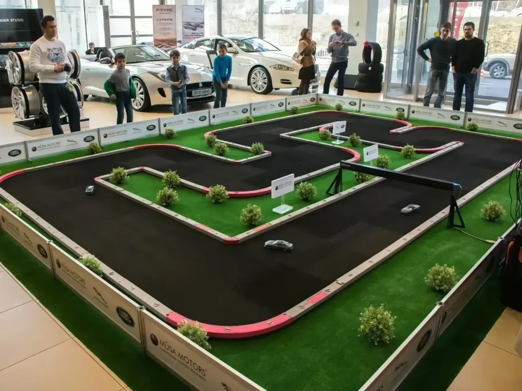 Circuito modular de radiocontrol rodeado de vehículos expuestos y asistentes en concesionario