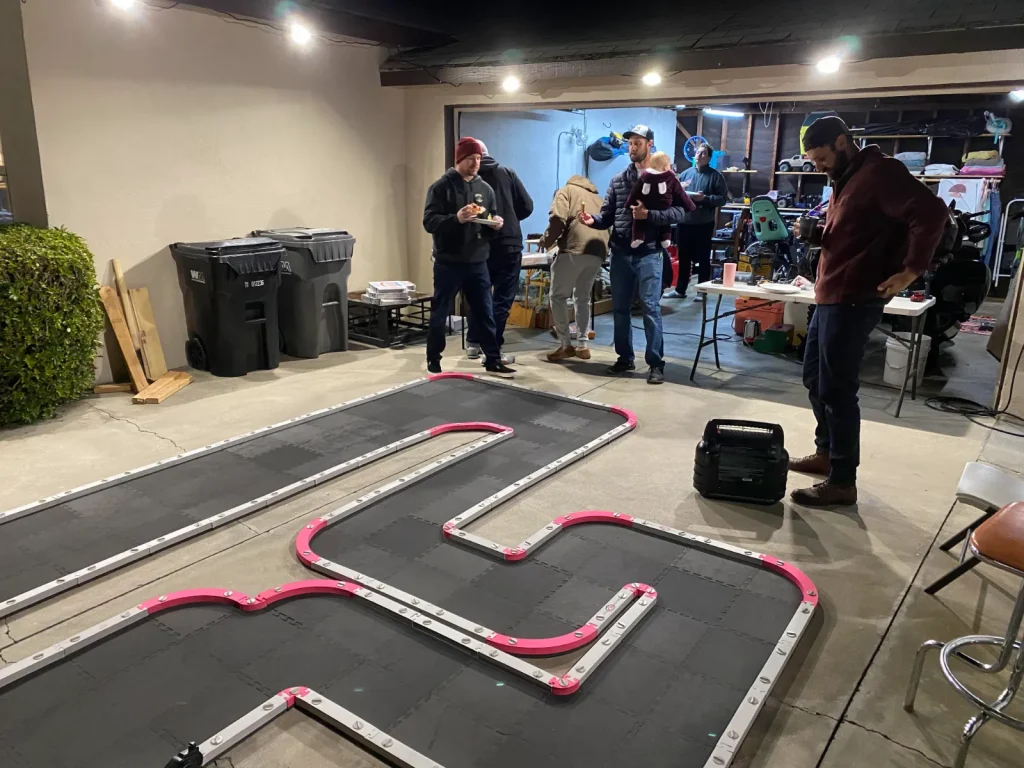 Participantes con mandos junto a una pista modular de radiocontrol en un evento de prensa