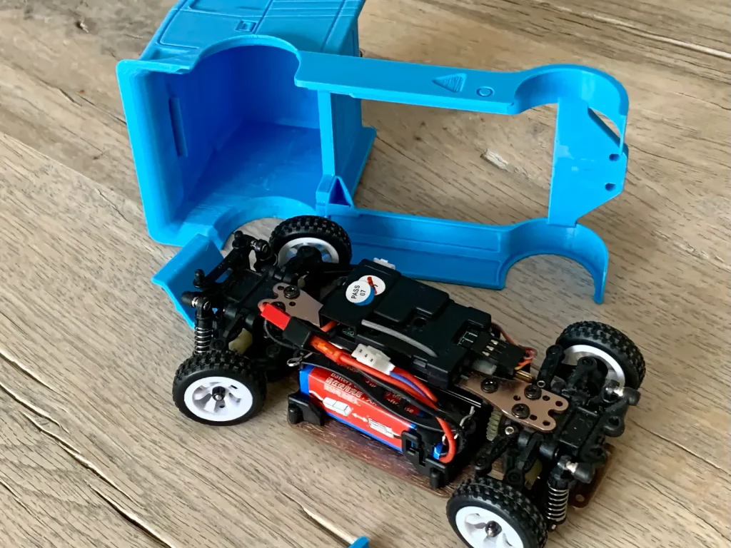 Chasis de coche de radiocontrol junto a una carrocería de camión azul personalizada