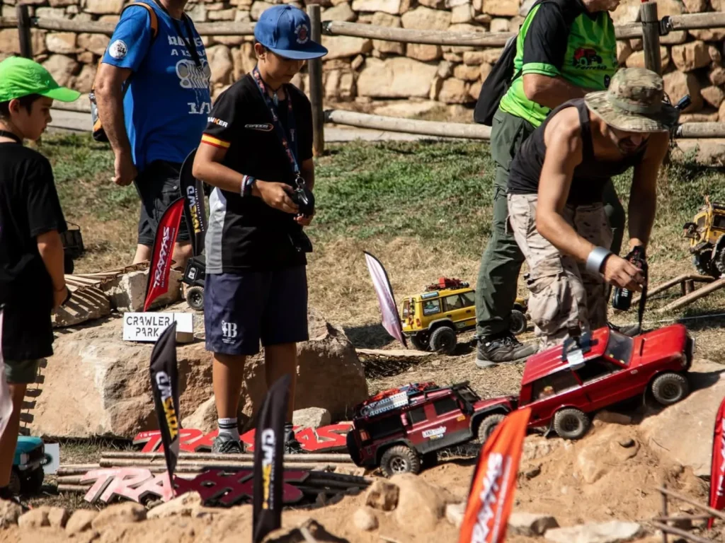 Participantes junto a un todoterreno de radiocontrol rojo en un recorrido de tierra y piedras en la Land Rover Party con Traxxas crawler 1:10
