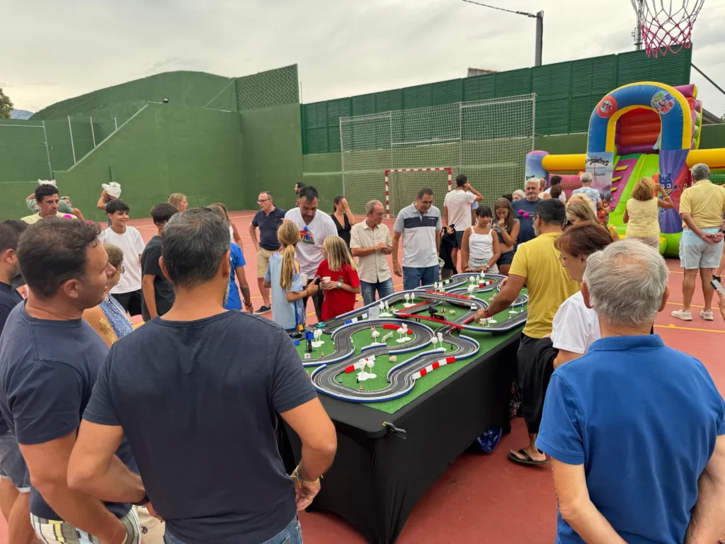 Adultos y niños jugando en un circuito de Scalextric Compact al aire libre en un Family day